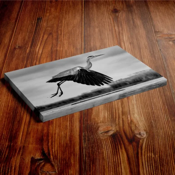 Nature-themed canvas wall art showing a heron with its wings spread in mid-flight over water.